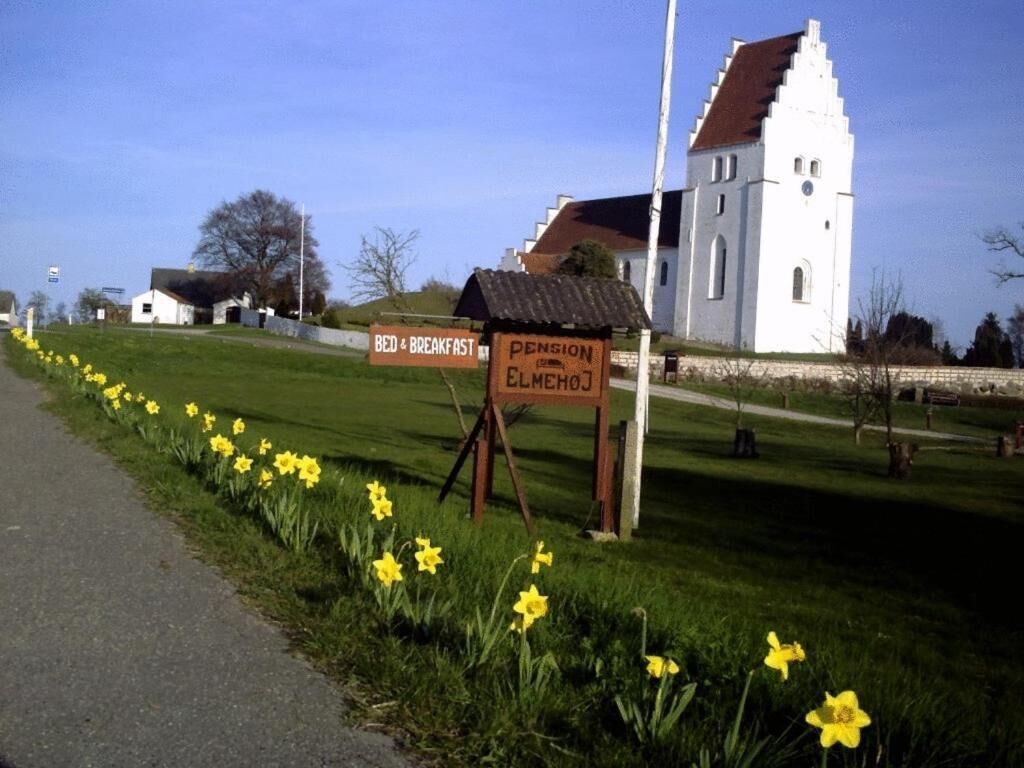 A white church with a bell tower, a sign for 'Bed & Breakfast', and a sign for 'Pension Elmehof'.