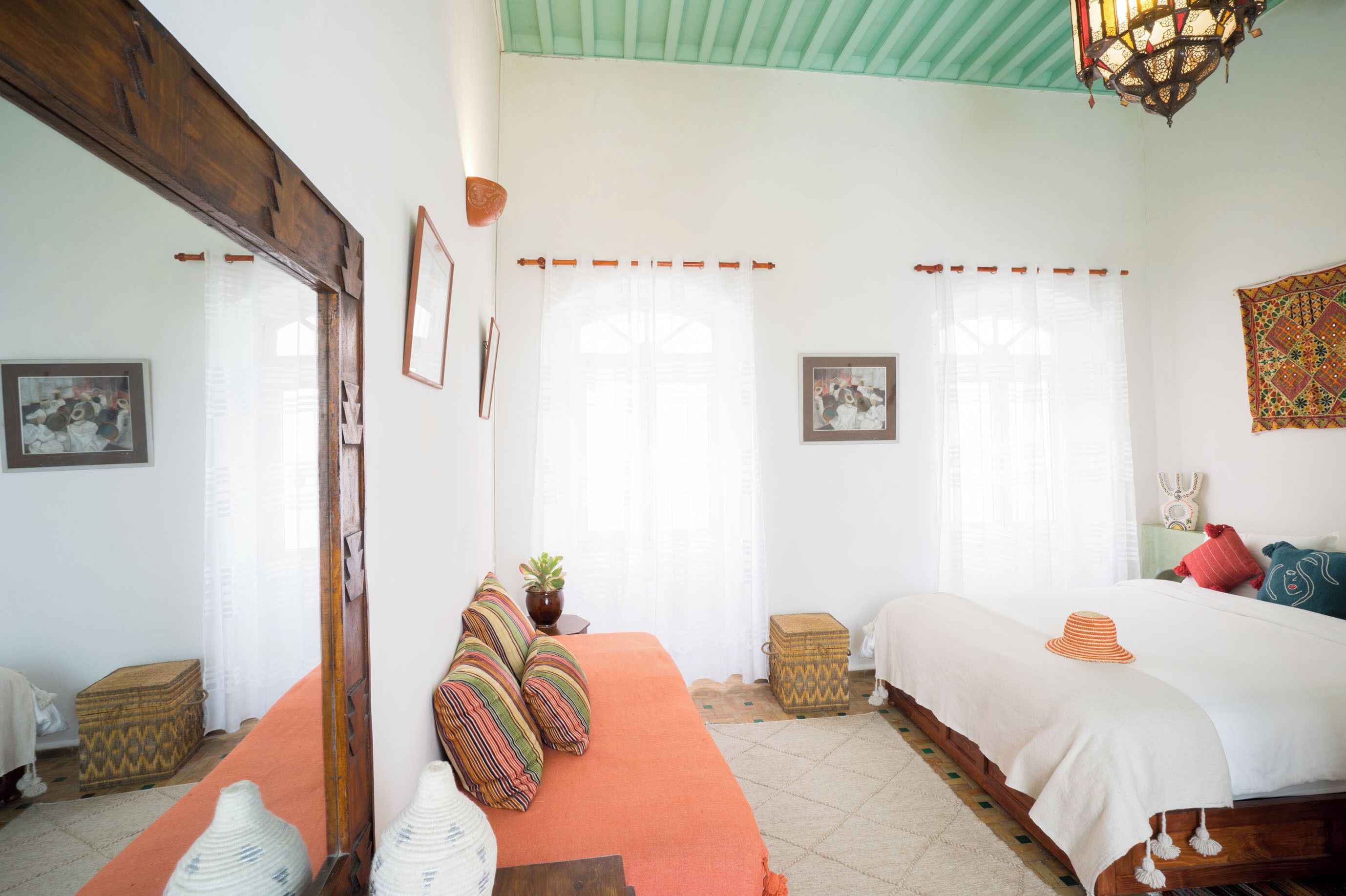 Un dormitorio con una cama, un banco y una ventana con cortinas.