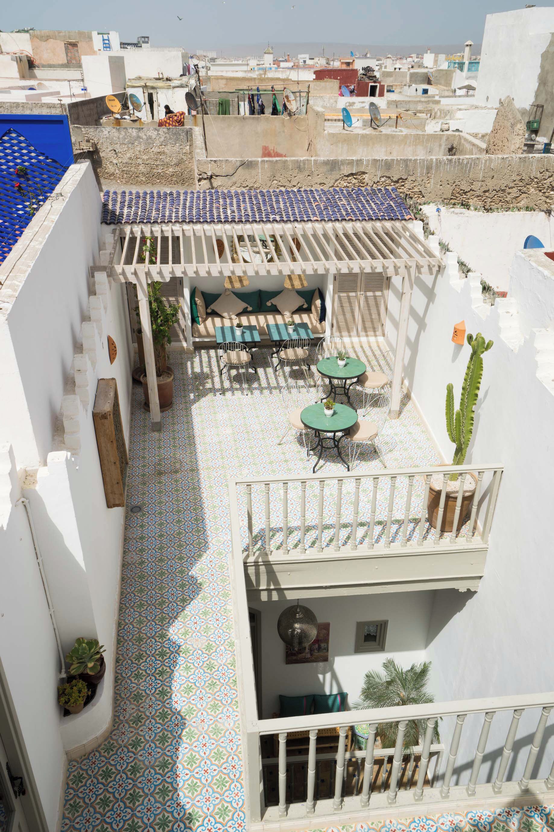 Terraço no telhado com piso estampado, mobiliário para área externa e vista panorâmica da cidade.