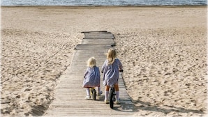 Une promenade en bois qui mène à une plage de sable bordée par l’eau.