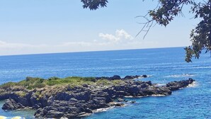 A coastal view with beach umbrellas, lounge chairs, and rocky outcrops. - Hotel Murmann (Maratea)