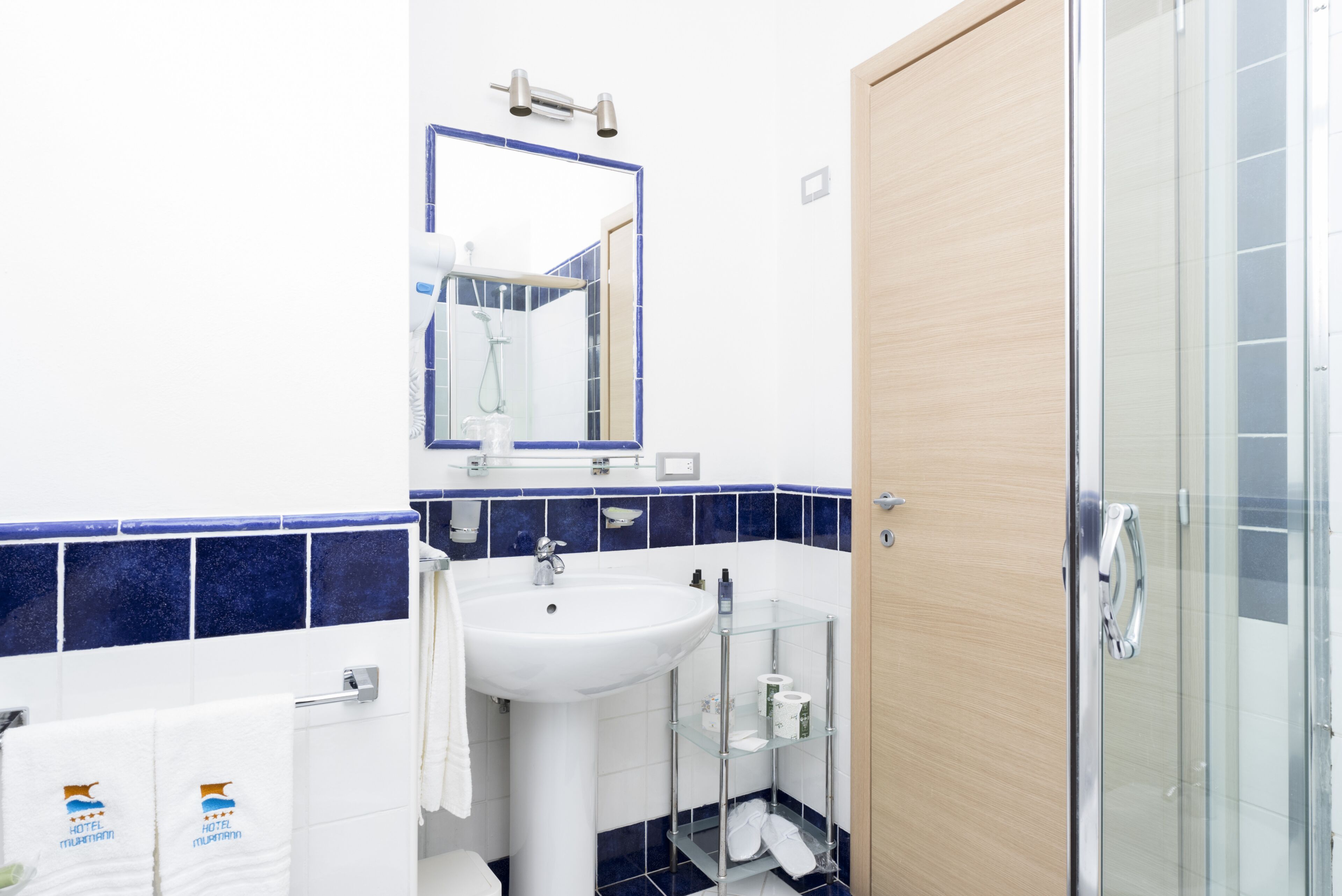 A modern bathroom with a white sink, a mirror, and a glass shower enclosure.