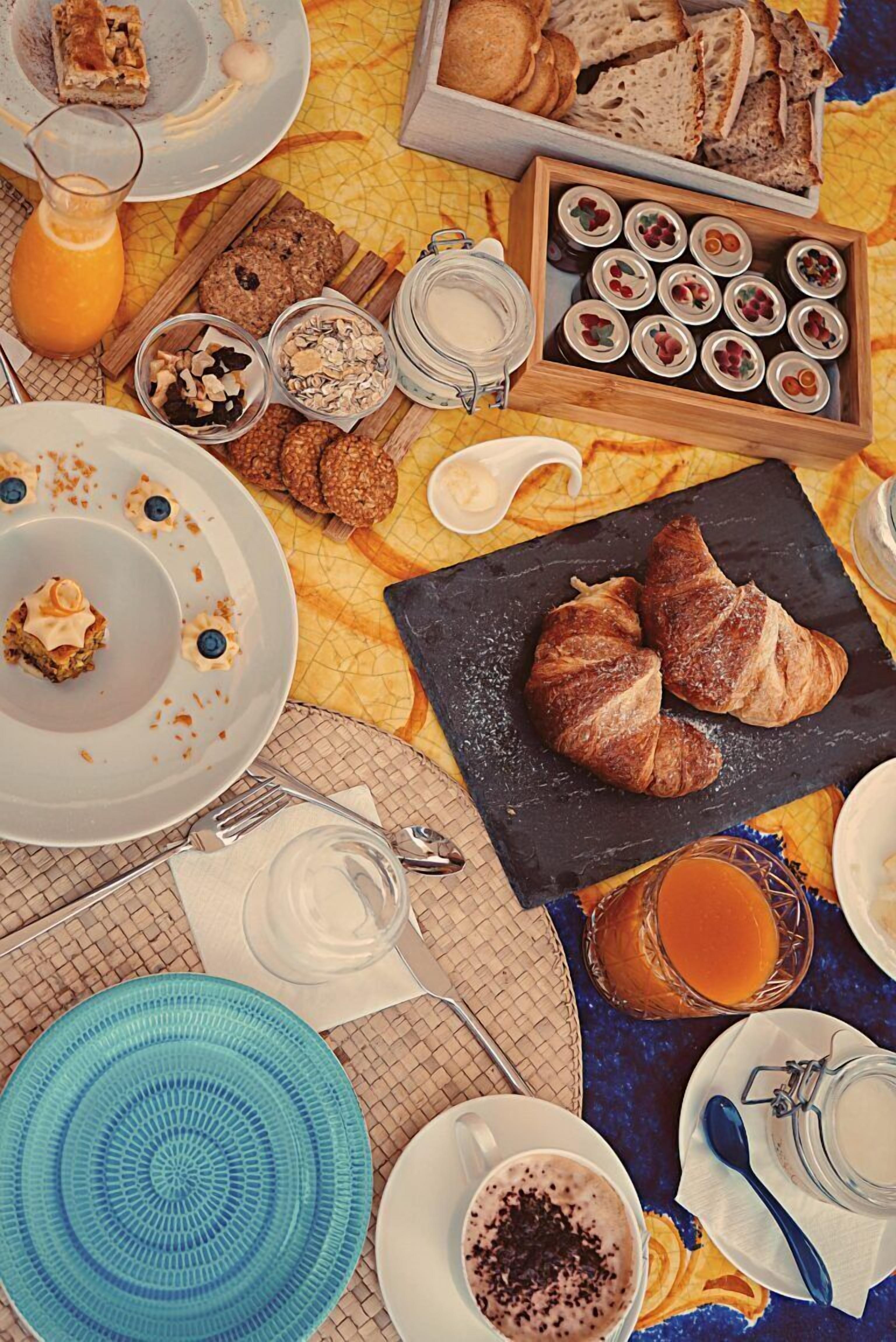 En frukostuppdukning med croissanter, bakverk och olika sorters pålägg på ett bord.