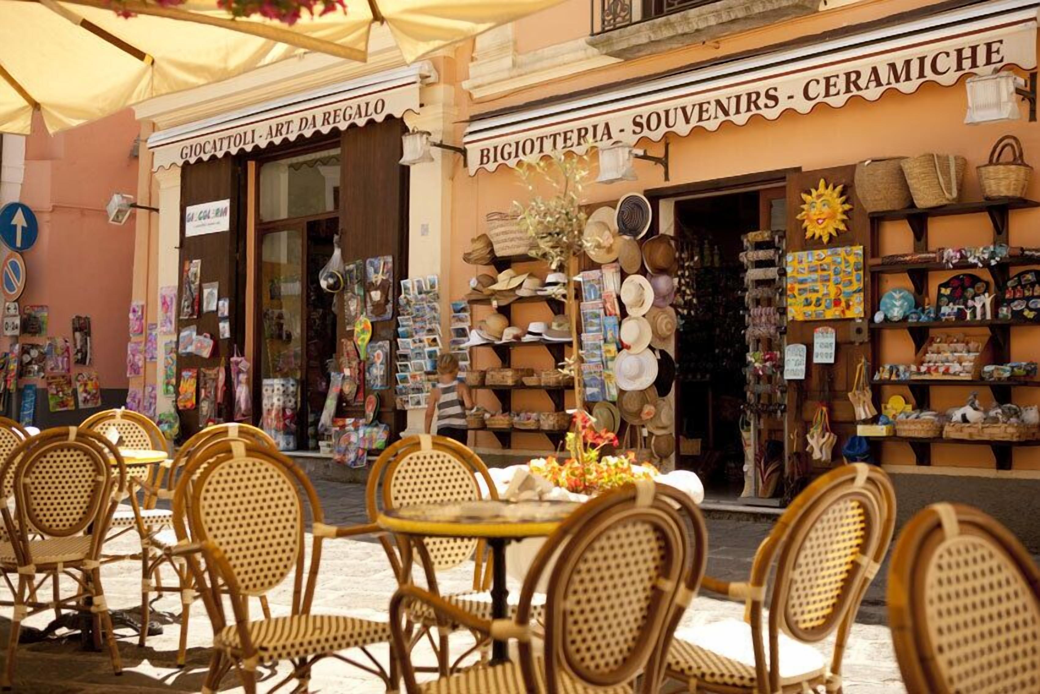 Una calle con mesas al aire libre y tiendas que venden recuerdos y cerámica.