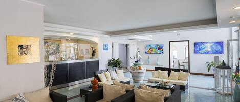 A spacious lobby with multiple seating areas, a reception desk, and various artworks on the walls.