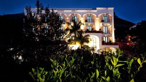 A multi-story building with balconies and large windows, surrounded by lush greenery. - Hotel Murmann (Maratea)
