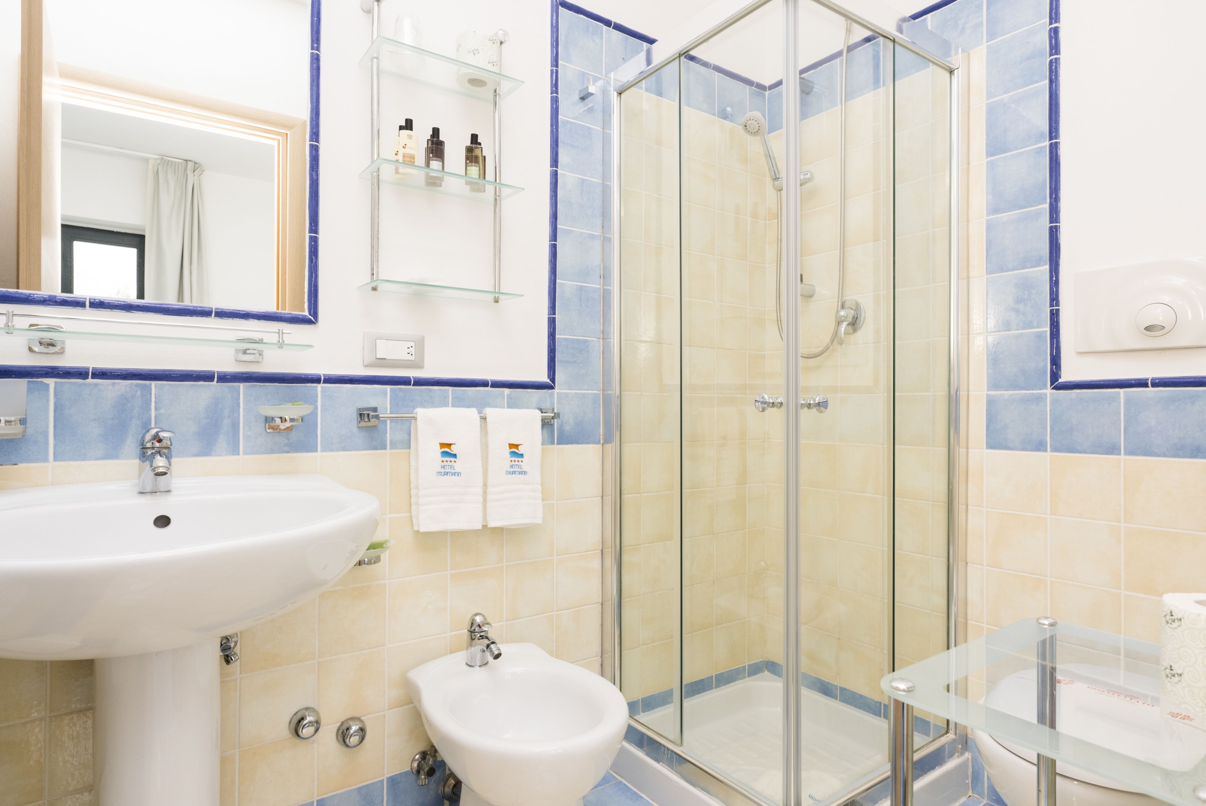 Un baño con cabina de ducha de vidrio, lavabo, bidé y espejo.