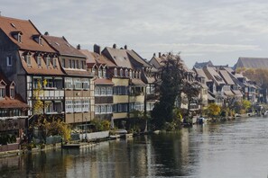 A row of traditional European-style buildings along a river, with a mix of residential and commercial uses. - Tandem (Bamberg)