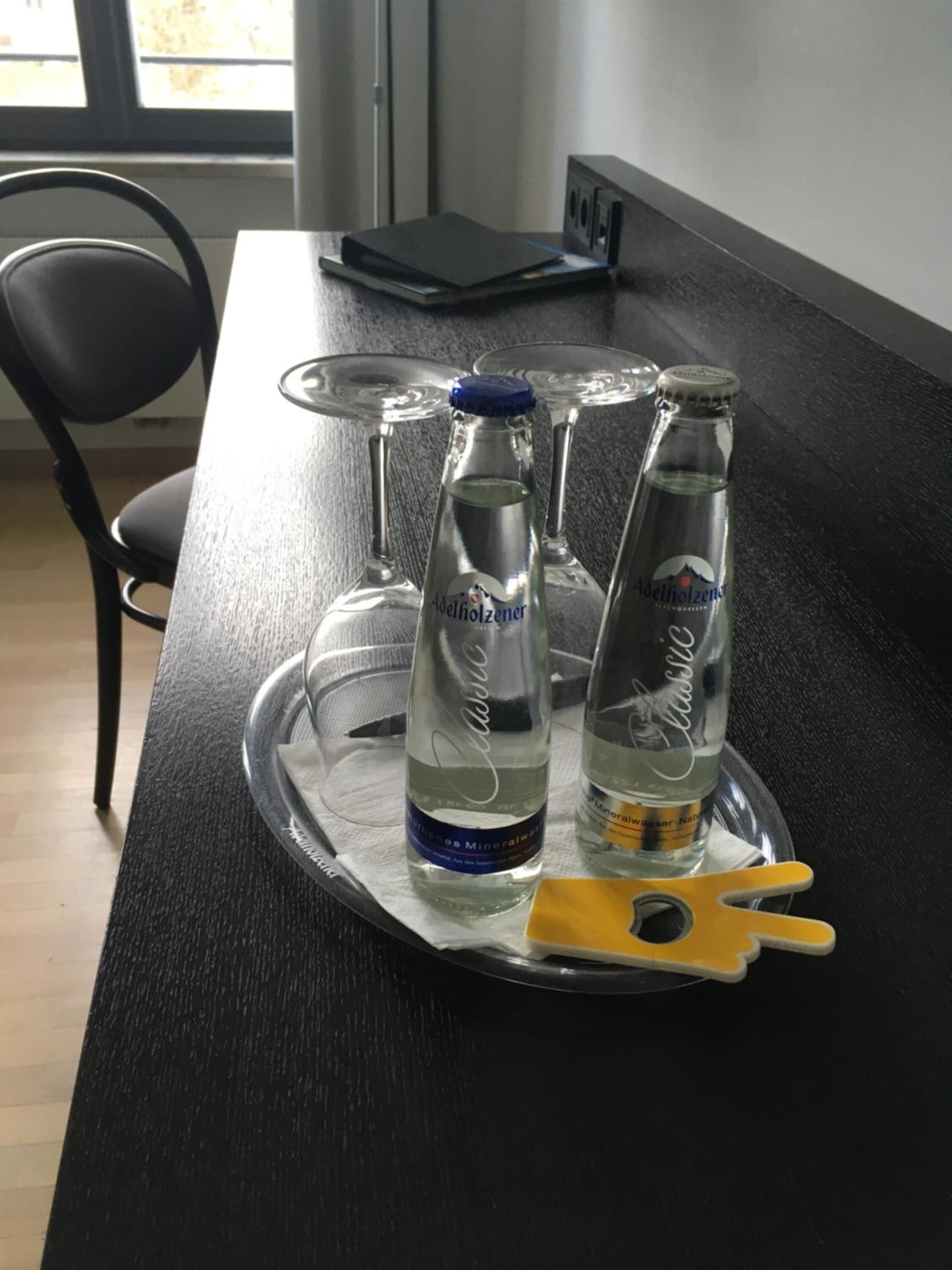 Uma bandeja com duas garrafas de água mineral e um objeto amarelo sobre uma mesa escura.
