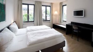A hotel room with a large bed, a desk, a chair, and a TV on the wall. - Tandem (Bamberg)