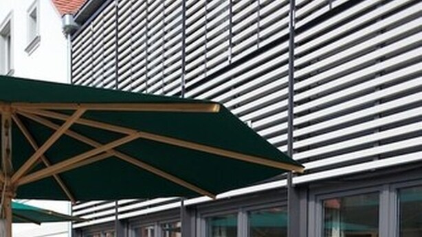 An outdoor seating area with tables and chairs, a large umbrella, and a potted plant. - Tandem (Bamberg)