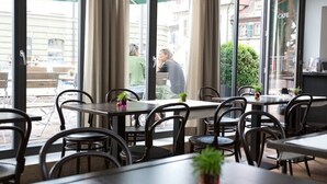 An indoor cafe with tables and chairs, large windows, and curtains. - Tandem (Bamberg)