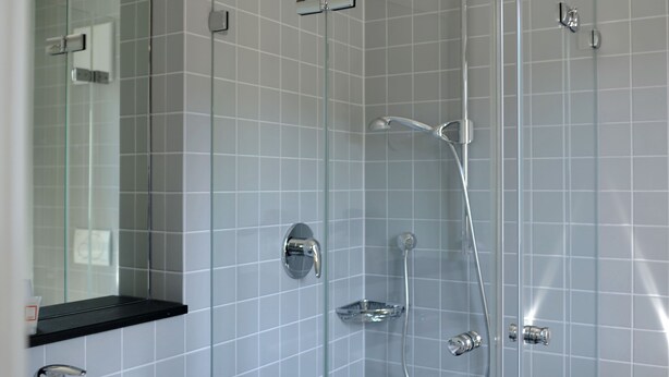 A modern bathroom with a glass-enclosed shower, a white sink, and a mirror.