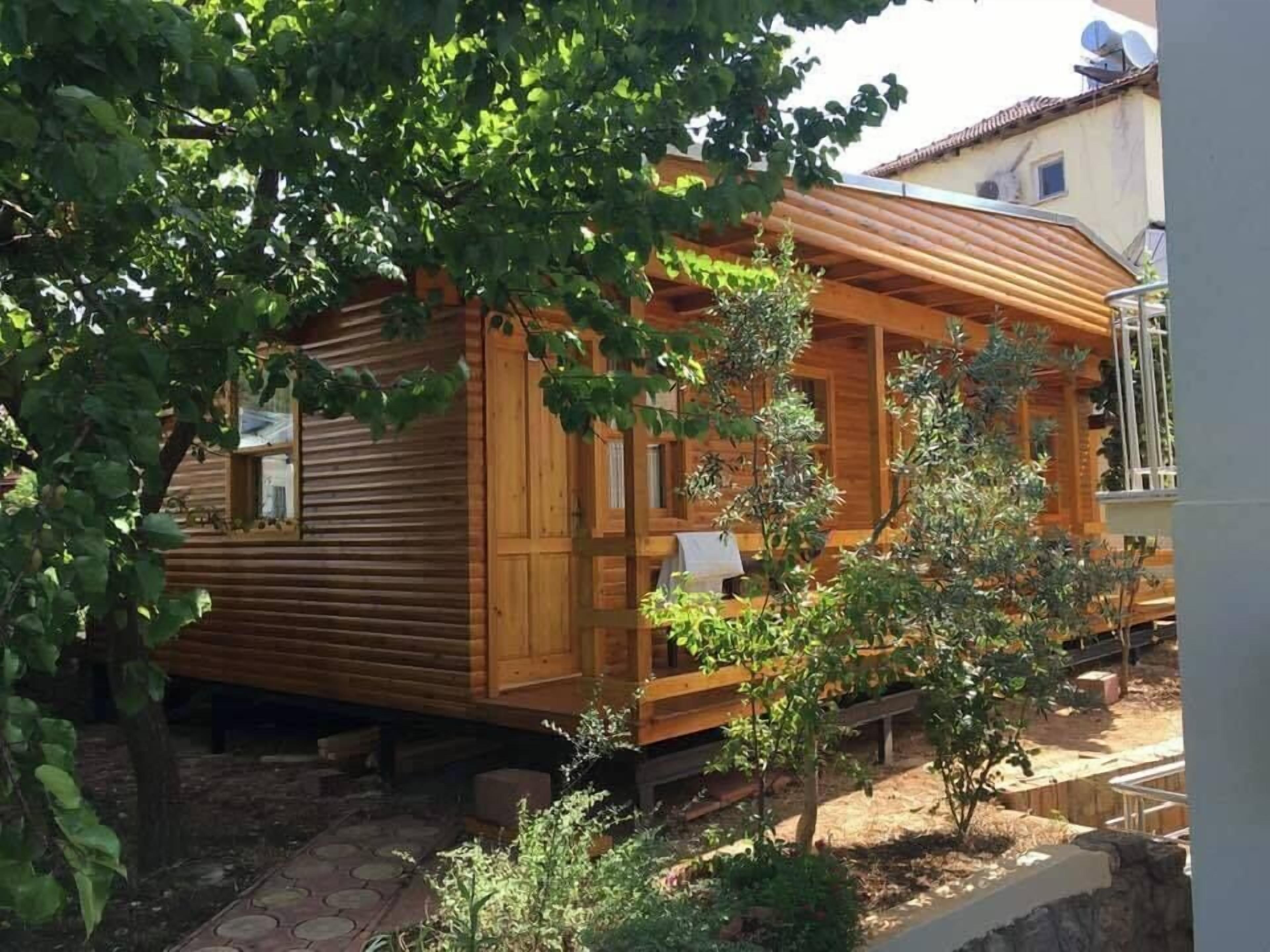 Una cabaña de madera con un porche, rodeada de follaje.