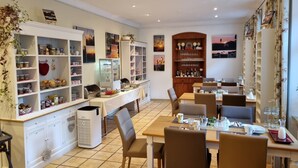 A dining area with a buffet setup, multiple seating arrangements, and decorative wall art. - Boutiquehotel Goldene Rose (Rothenburg ob der Tauber)
