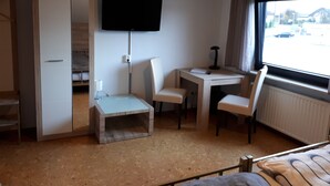 Ein Hotelzimmer mit Bett, Schreibtisch mit Stuhl, Fernseher und Fenster mit Ausblick.