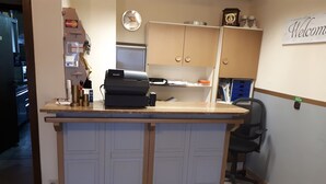 Ein Empfangsschalter mit Kasse, einer Uhr und einem 'Welcome'-Schild.