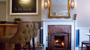 A cozy room with a fireplace, a bar area, and a chalkboard sign reading "Welcome to The White Horse Inn". - The White Horse Inn (Pulborough)
