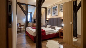 A bedroom with a large bed, a wooden wardrobe, and a mirror. - Pension U Lilie (Prague)