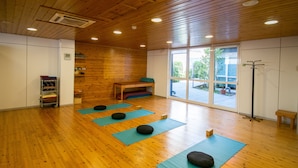 A spacious room with wooden floors and walls, large windows, and yoga mats arranged for practice. - Accommodation de Salut Somlom (Sant Esteve de Palautordera)