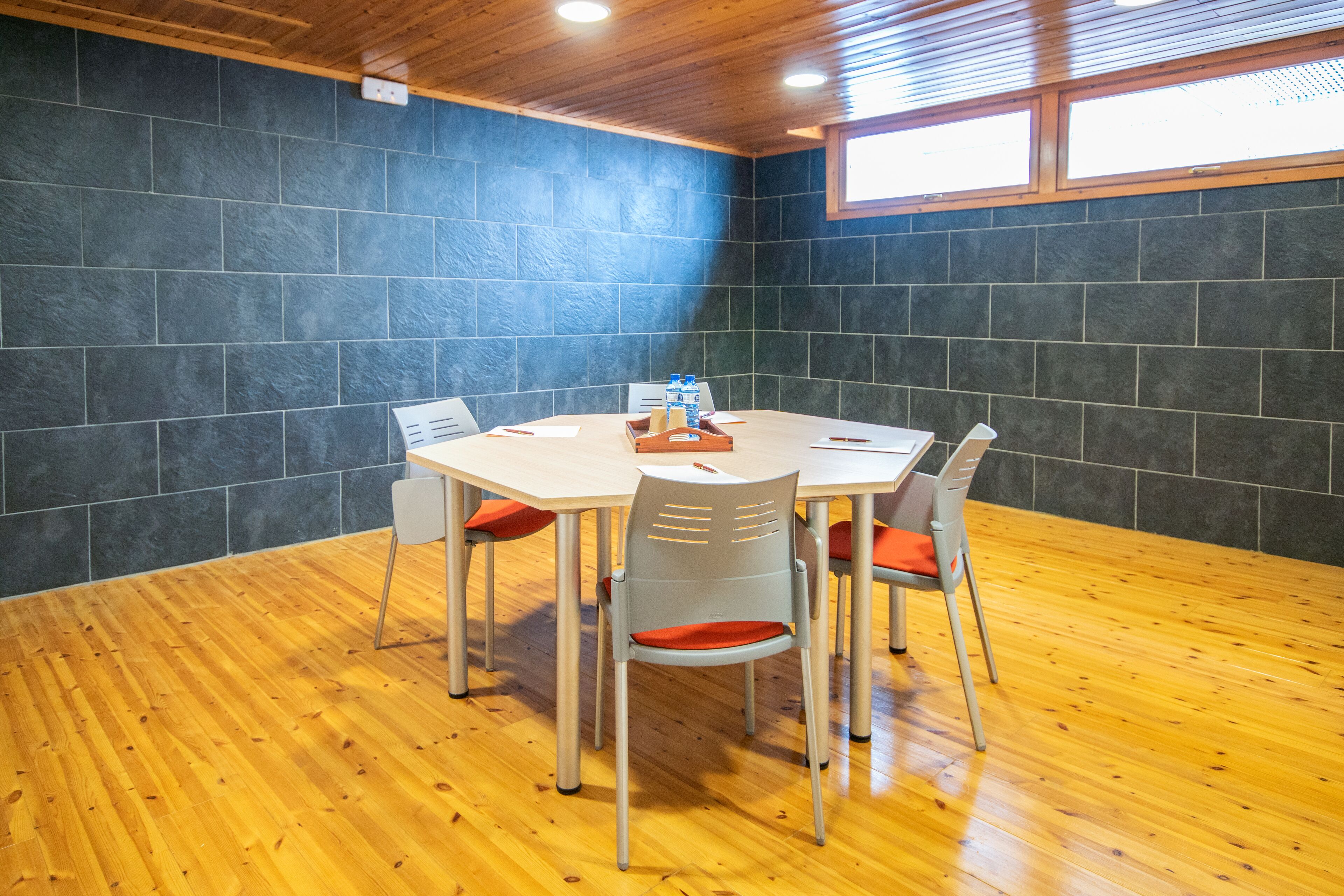 Un salón de conferencias con una mesa redonda, cuatro sillas y piso de madera.