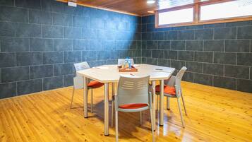 Un salón de conferencias con una mesa redonda, cuatro sillas y piso de madera.
