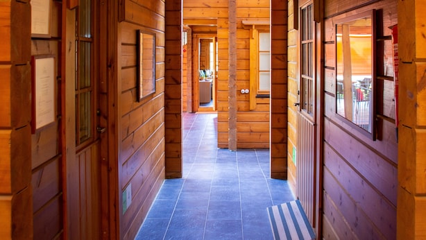 A wooden hallway with a tiled floor, wooden doors, and a view into a dining area. - Accommodation de Salut Somlom (Sant Esteve de Palautordera)