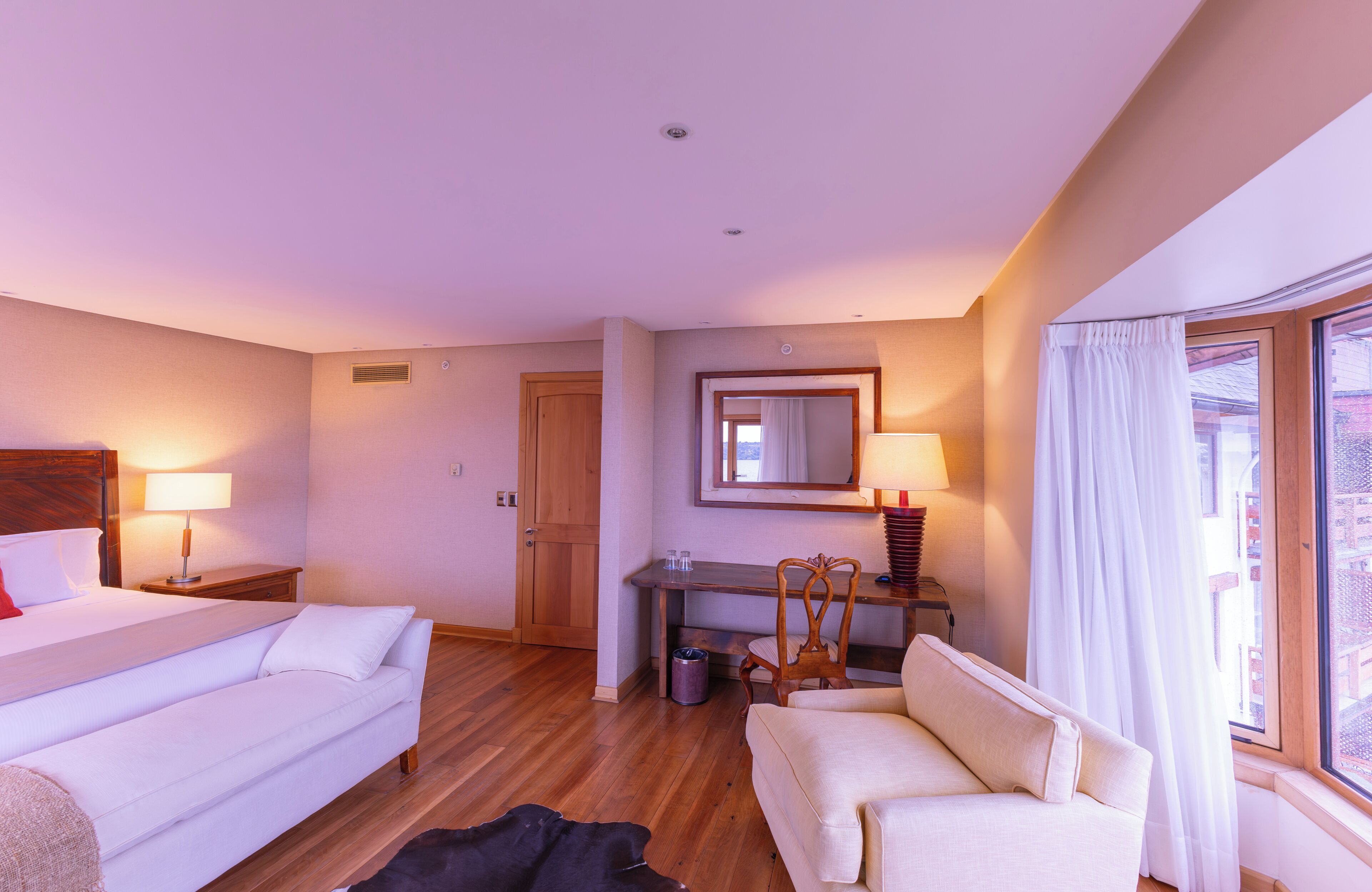 A hotel room with a bed, a desk, a chair, and a sofa.