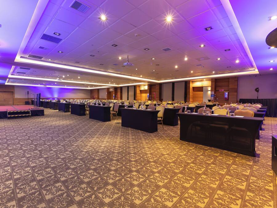A large conference room with a patterned carpet, multiple tables, and chairs arranged for meetings.