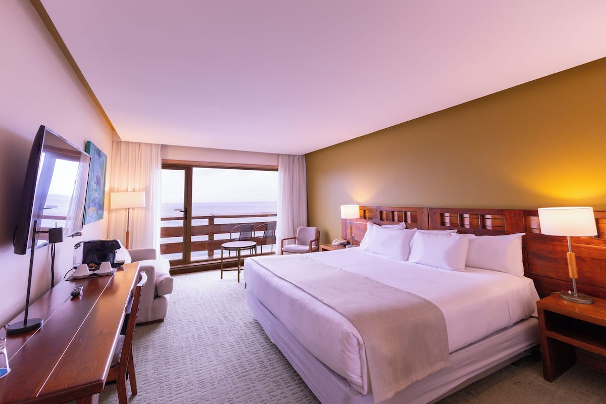 A hotel room with a bed, a desk, a chair, a TV, and a window with a view.