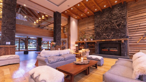 Un salón amplio con chimenea, sofás y techo de madera.