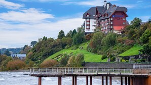 Un hotel con fachada roja y blanca, varios balcones y vistas al río.