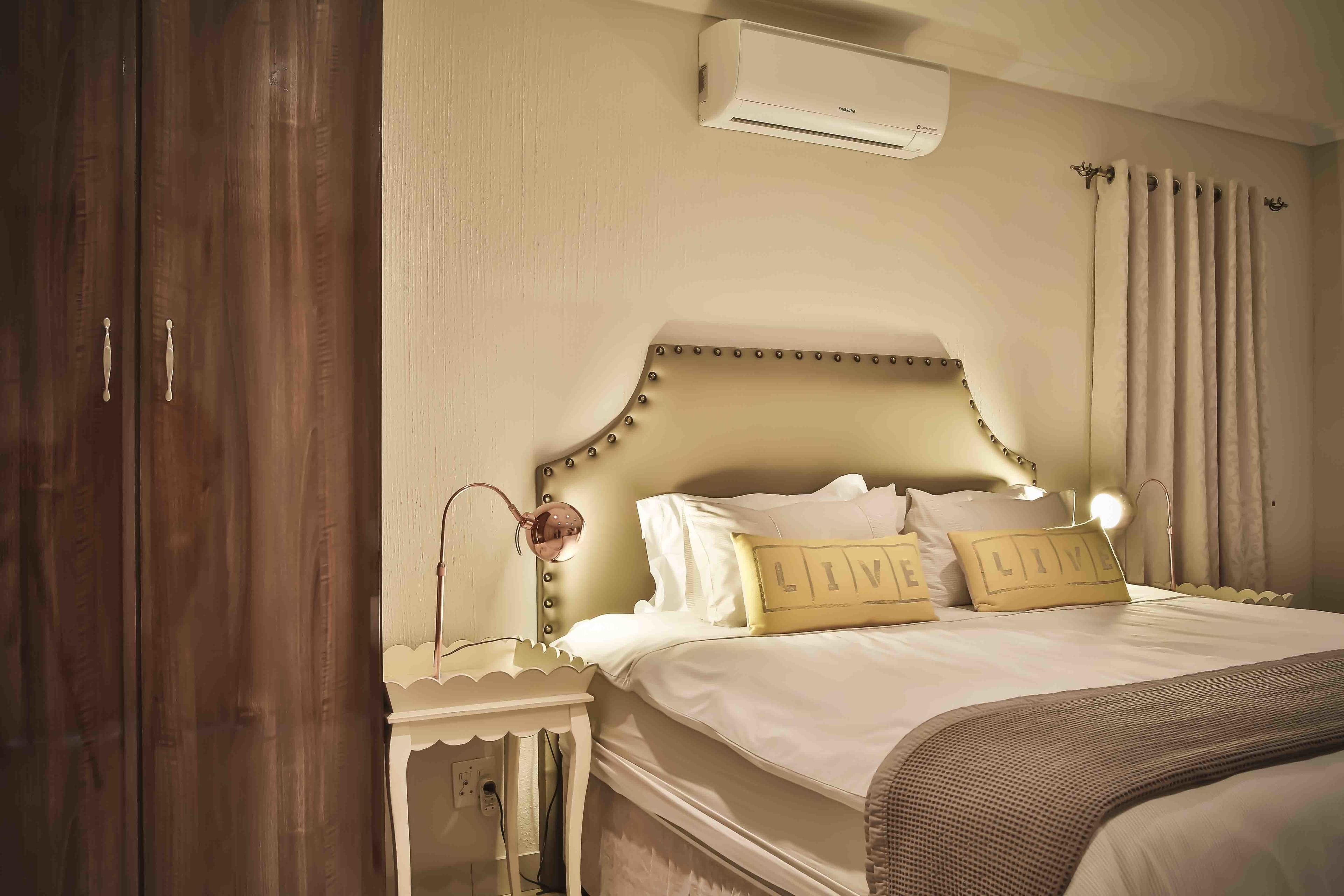 Un dormitorio con cama, lámparas de noche, mesita de noche, aire acondicionado y armario.