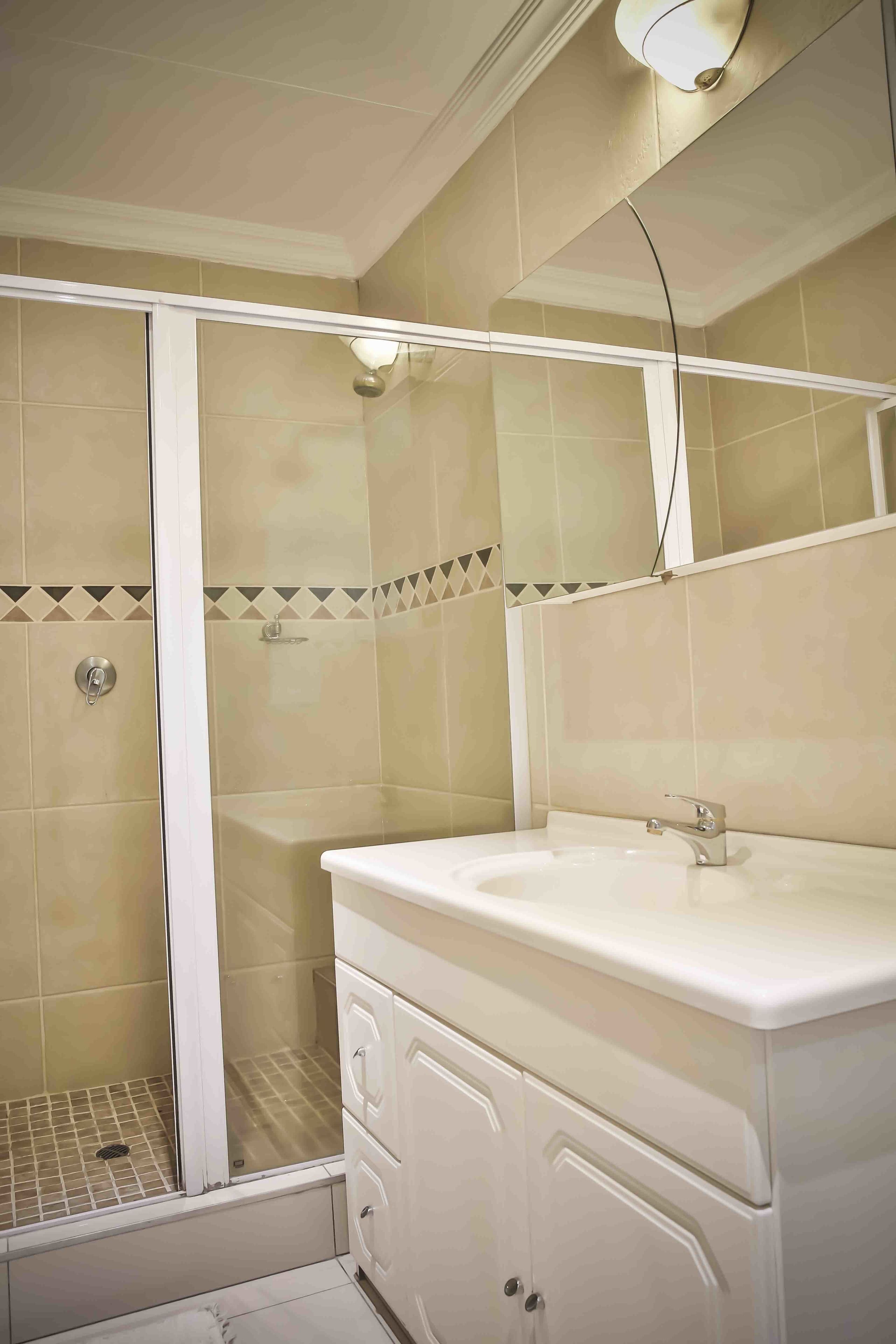 A bathroom with a shower, a sink, and a mirror.
