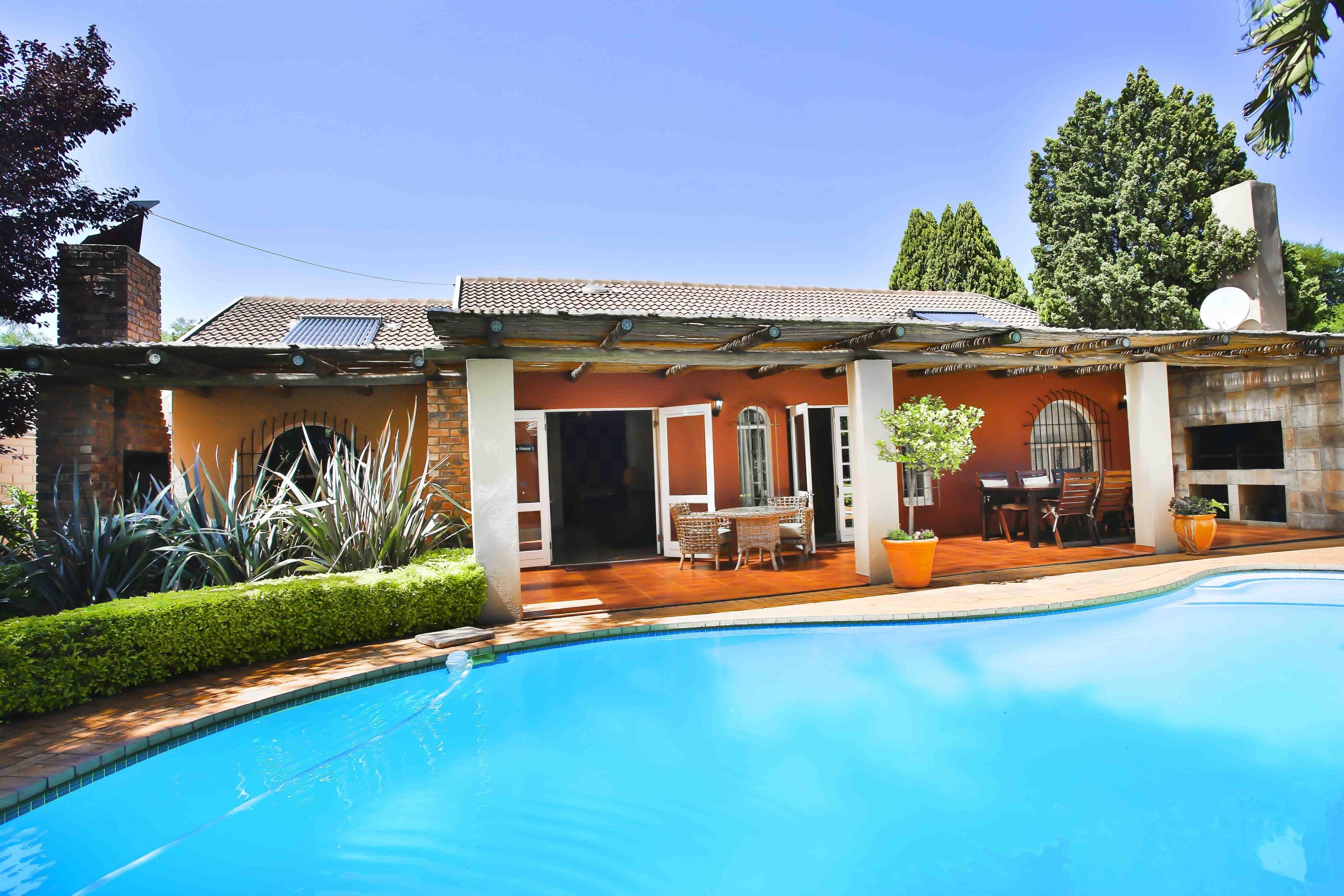 A house with a swimming pool, a patio with outdoor furniture, and a garden with various plants.