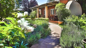 Un sendero de jardín que conduce a una casa con una escultura singular y un patio.