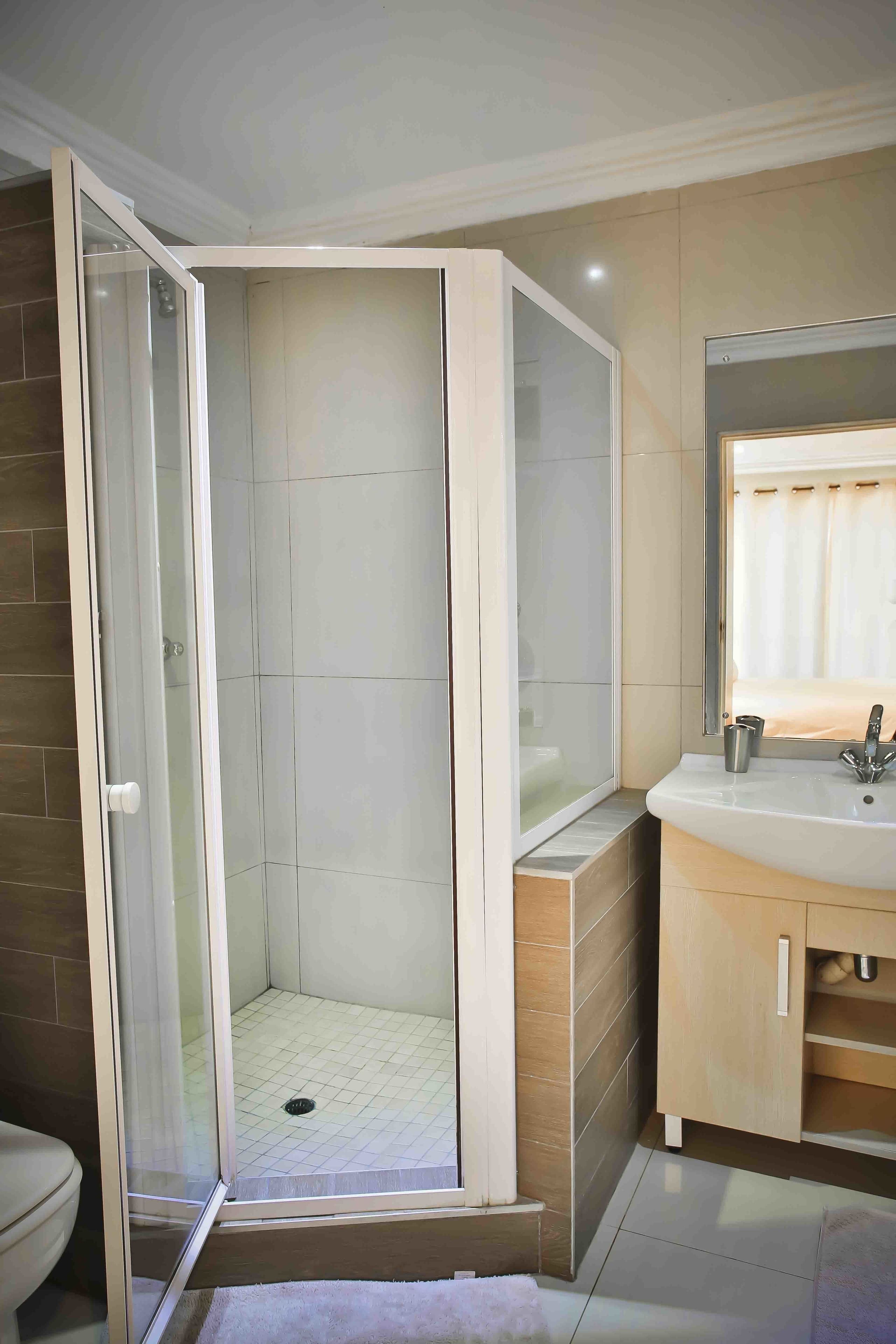 A bathroom with a glass-enclosed shower, a sink with a mirror, and a toilet.