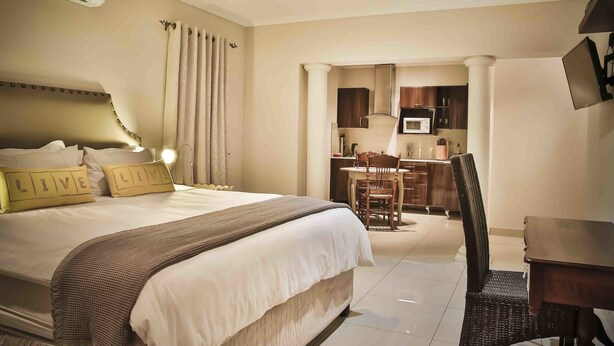 Habitación de hotel con cama, escritorio, silla, mesa de comedor, zona de cocina y aire acondicionado.