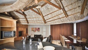 Una cocina con una isla grande, armarios de madera, un microondas y un comedor con una mesa larga y sillas.