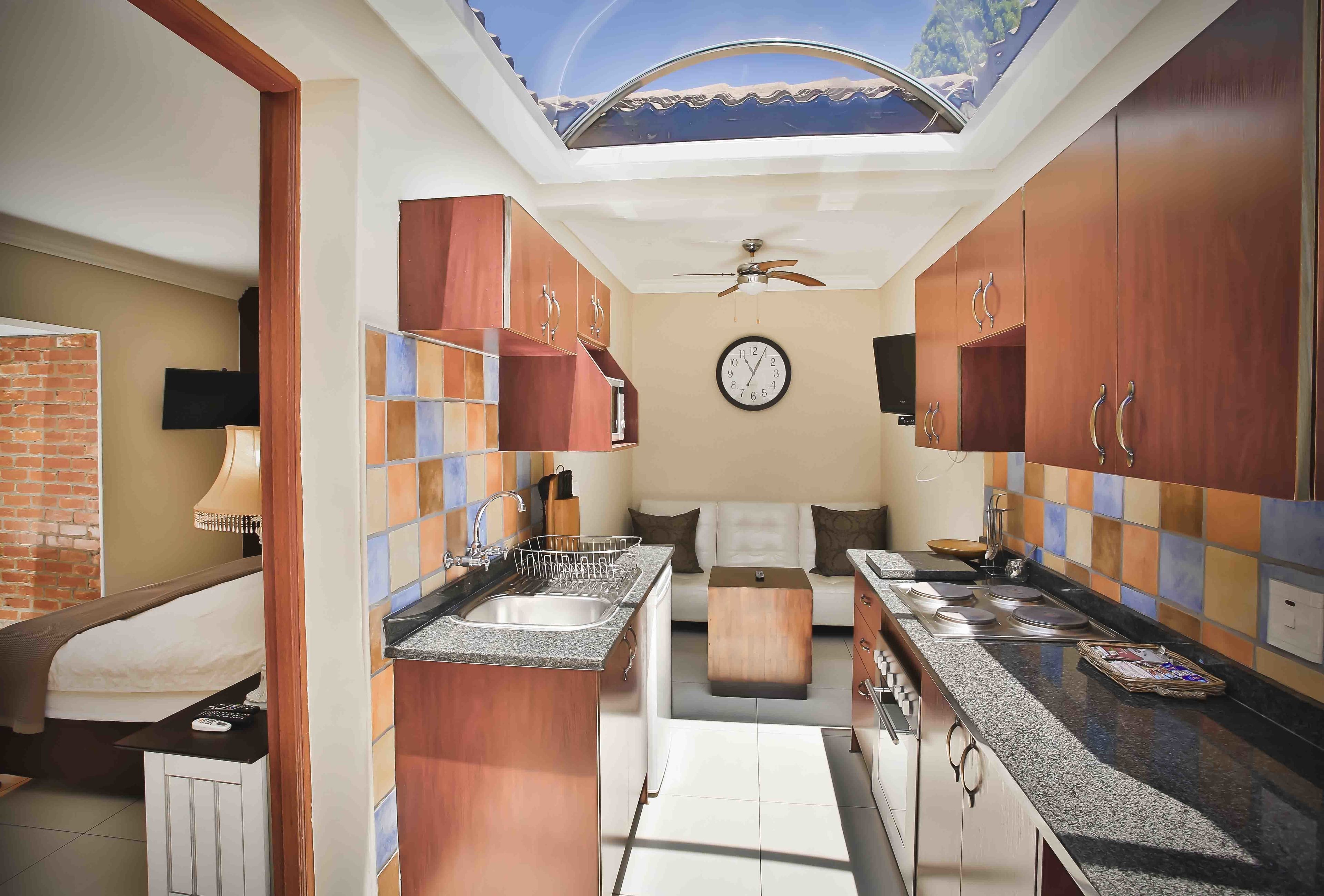 Una cocina compacta con una isla central, un comedor con sofá y un ventilador de techo.