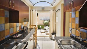 Cocina compacta con tragaluz, zona de comedor con sillas y vistas a un espacio exterior.