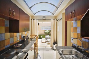 Cocina compacta con tragaluz, zona de comedor con sillas y vistas a un espacio exterior.