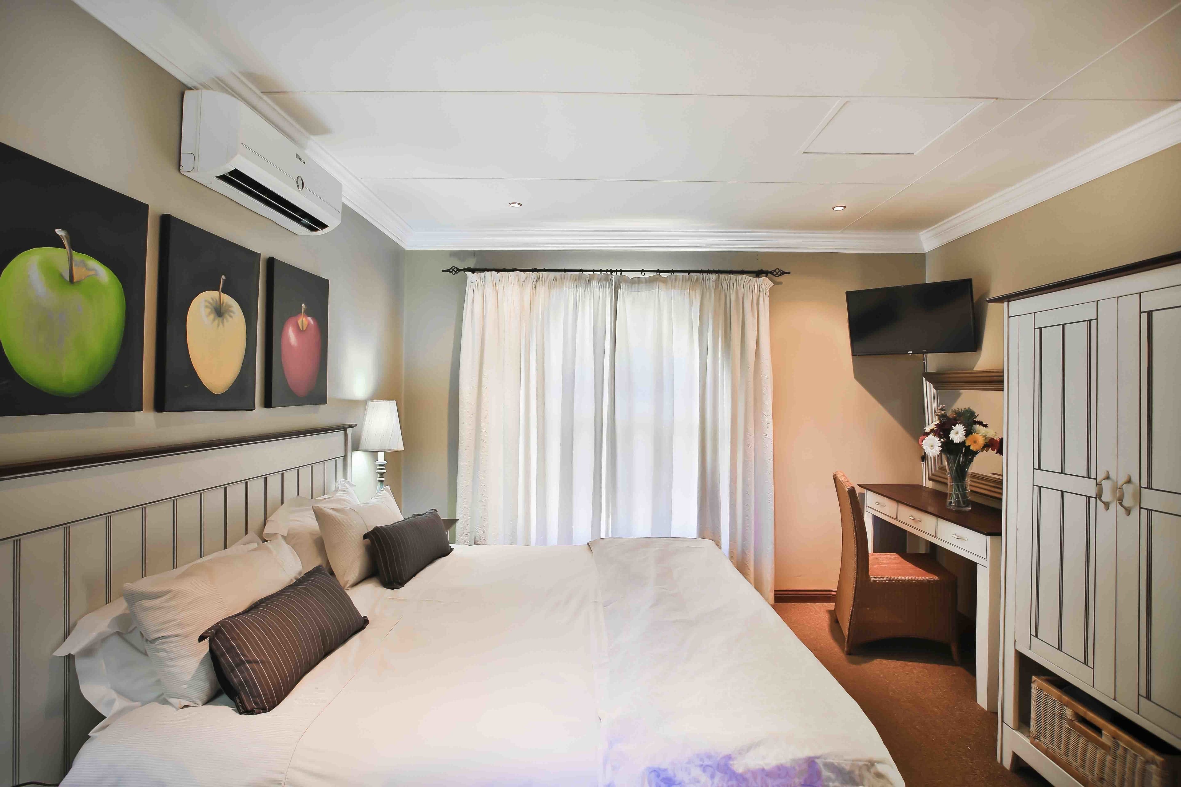 A hotel room with a bed, a desk, a TV, and a wardrobe.