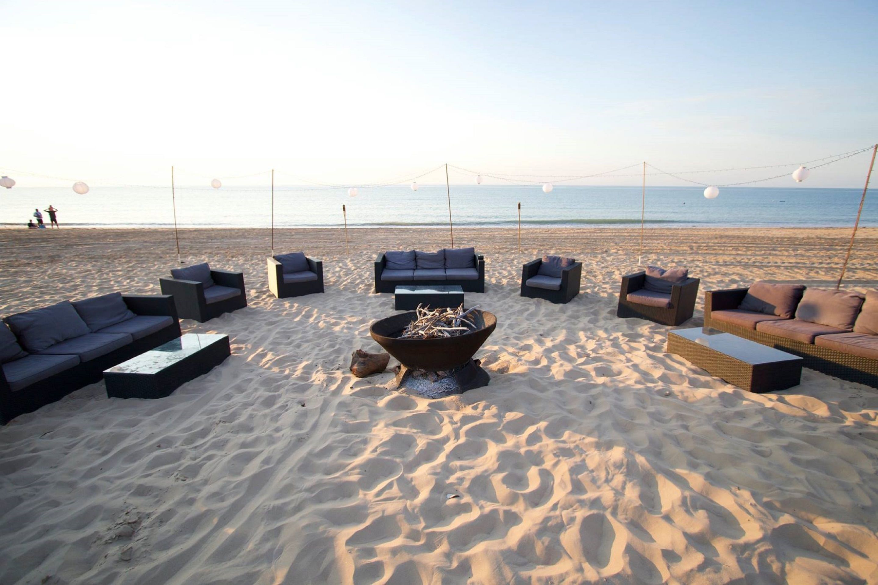 A beachside lounge with outdoor seating and a central fire pit.