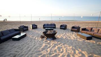 A beachside lounge with outdoor seating and a central fire pit.