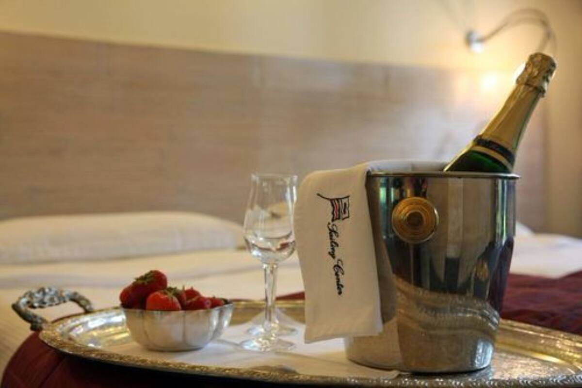 A champagne bottle in a metal bucket with a towel, a glass of water, and a bowl of strawberries on a tray.