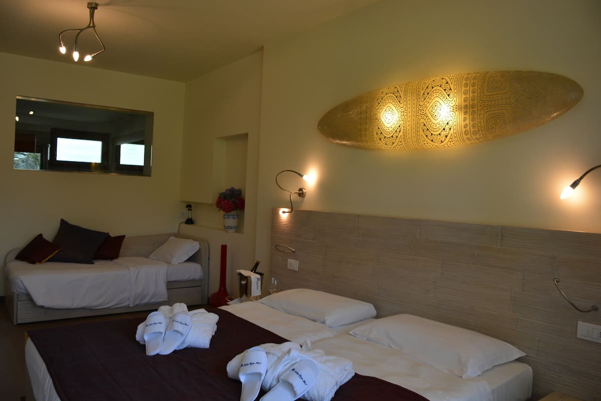 A hotel room with two beds, a large mirror, and a decorative wall light.