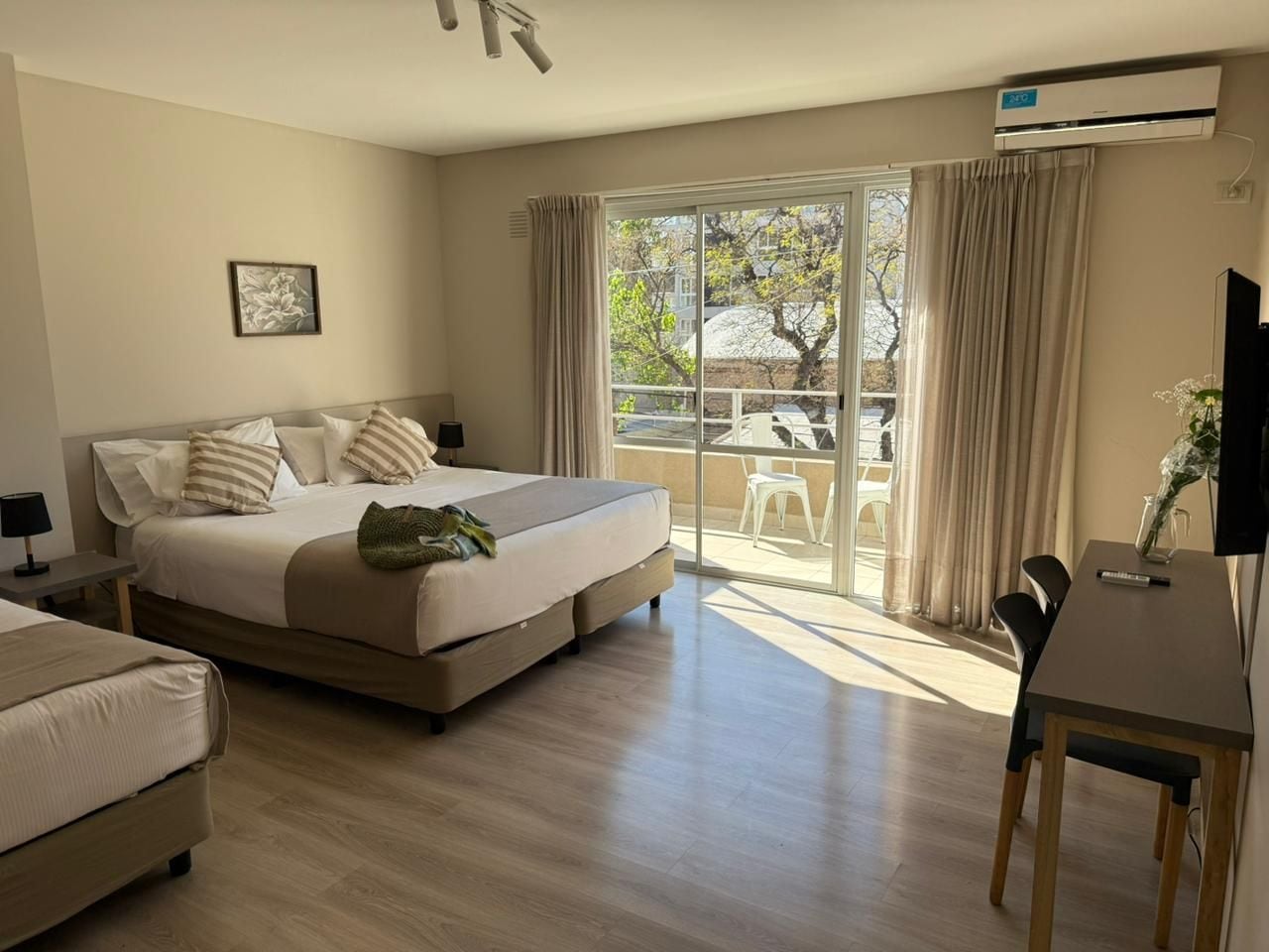 Quarto de hotel com cama, escrivaninha e varanda com vista.