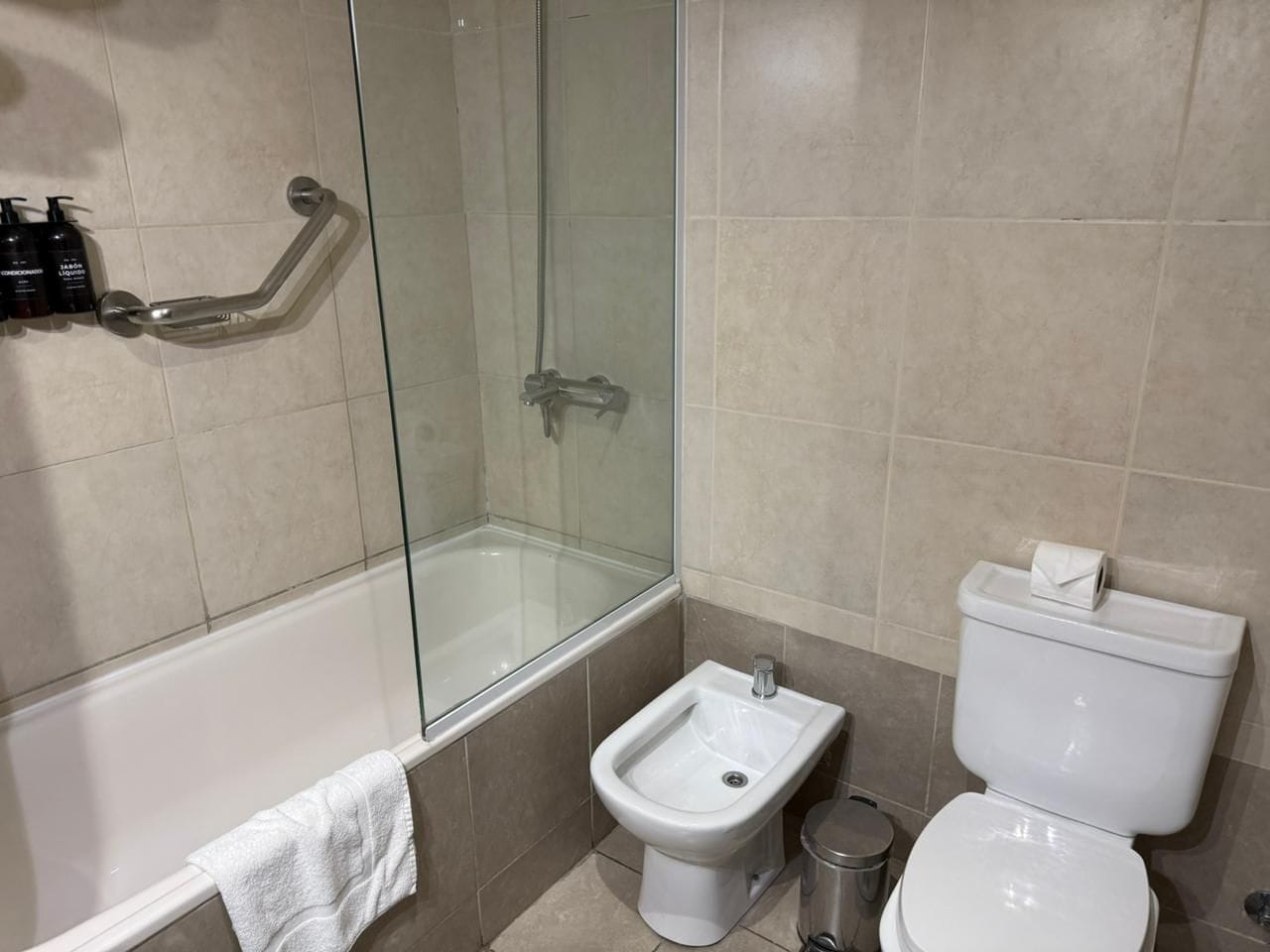 Et badeværelse med bruseniche i glas, et bidet, toilet og badekar.