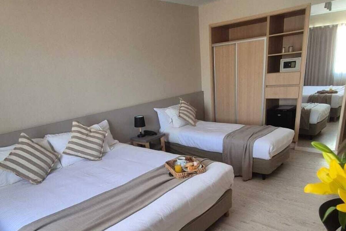 A hotel room with two beds, a wardrobe, a desk, and a chair.